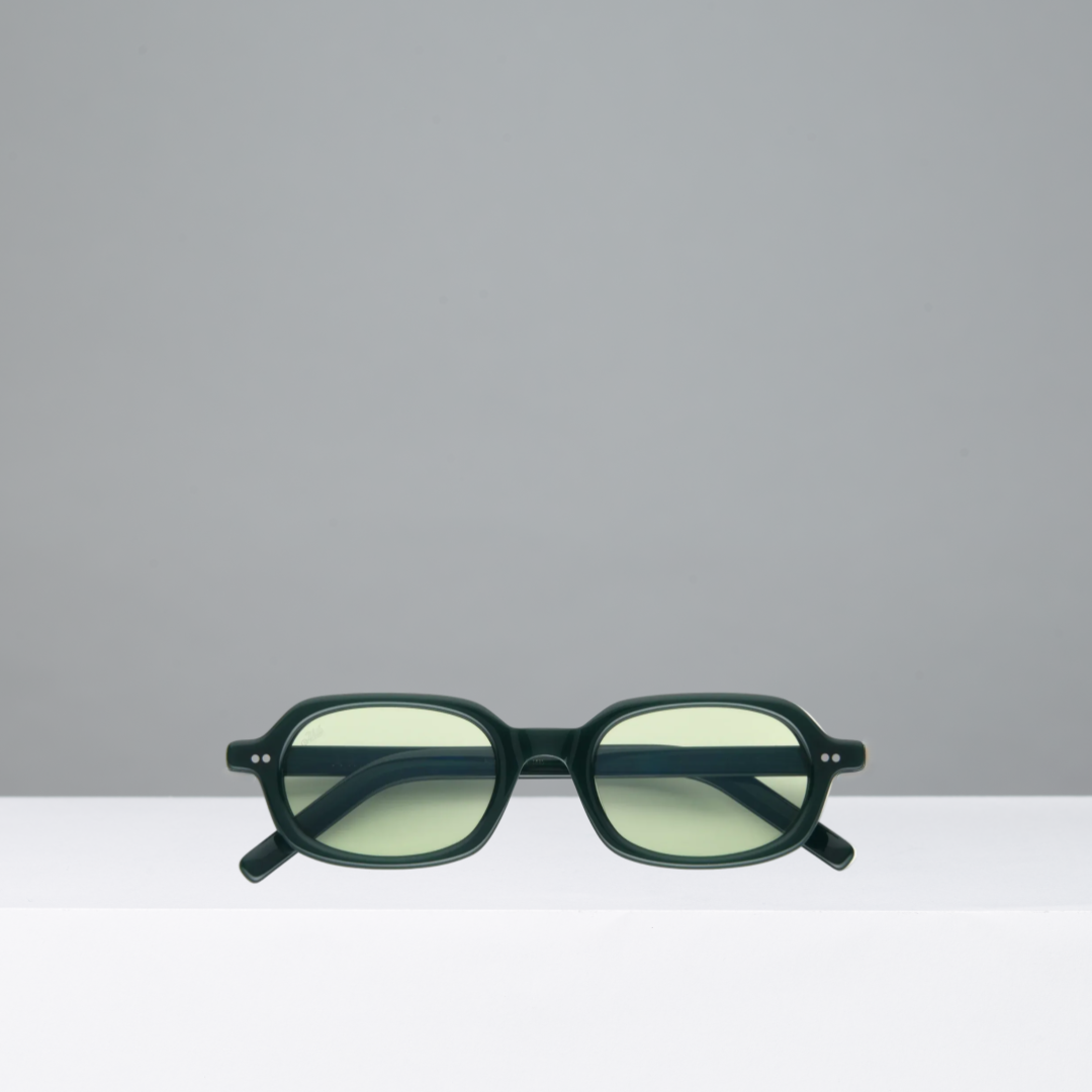 Green sunglasses on a white surface with a gray background