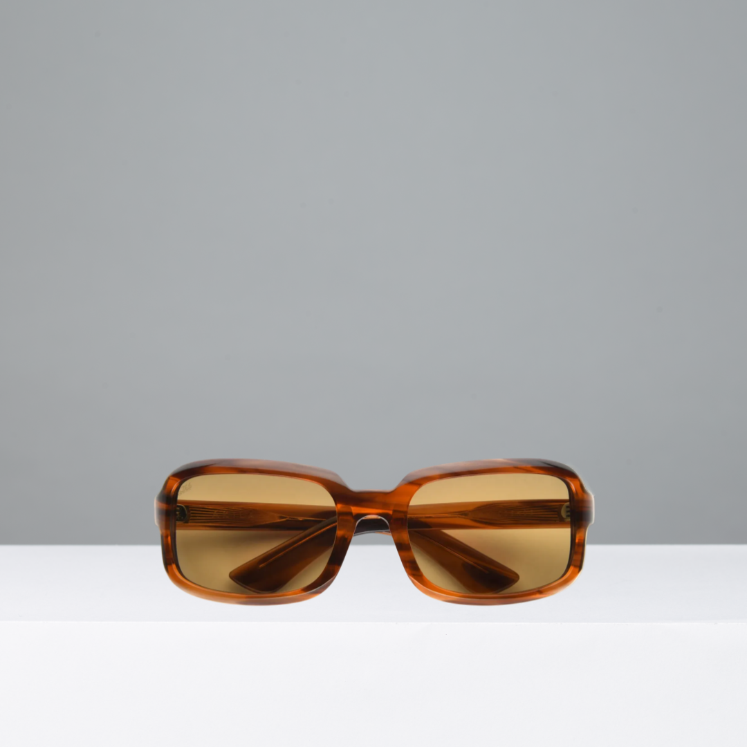 Brown sunglasses on a white surface with a gray background