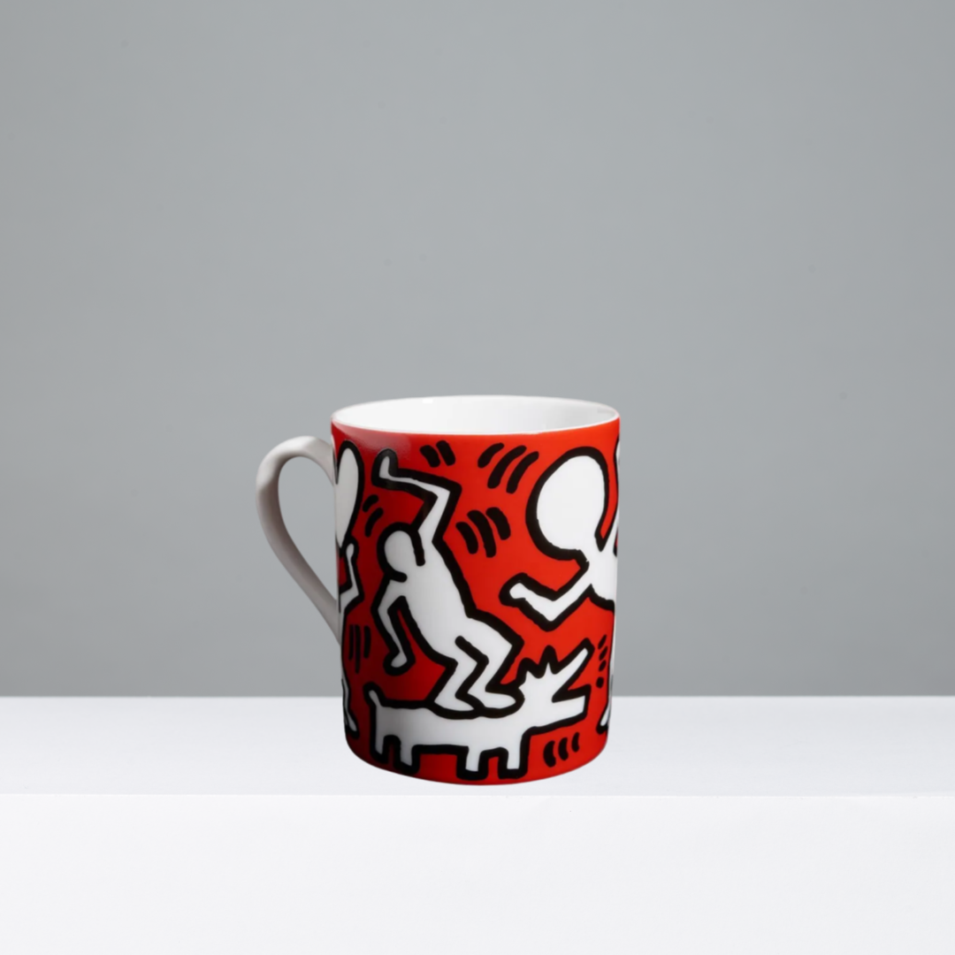 Mug featuring a Keith Haring design in black, white, and red on a gray background