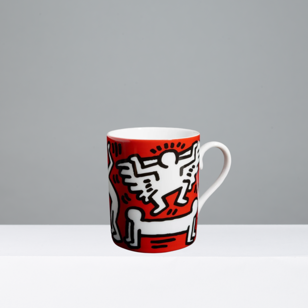 Mug featuring a Keith Haring design in black, white, and red on a gray background