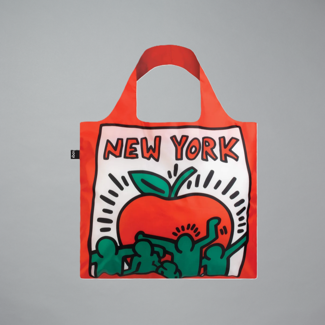 A red reusable tote bag with a New York themed artwork by Keith Haring on a gray background