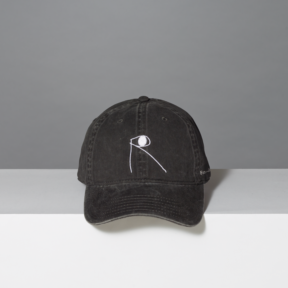 A washed black baseball cap with a white minimalist line-art logo on the front, displayed on a white surface against a gray background.