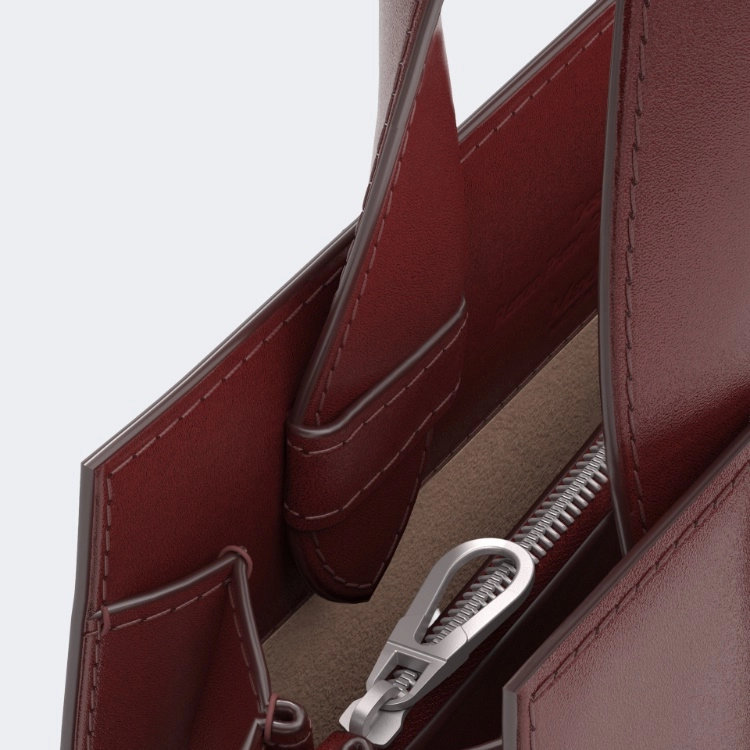 Close-up of a red leather bag with a silver zipper pocket on a white background