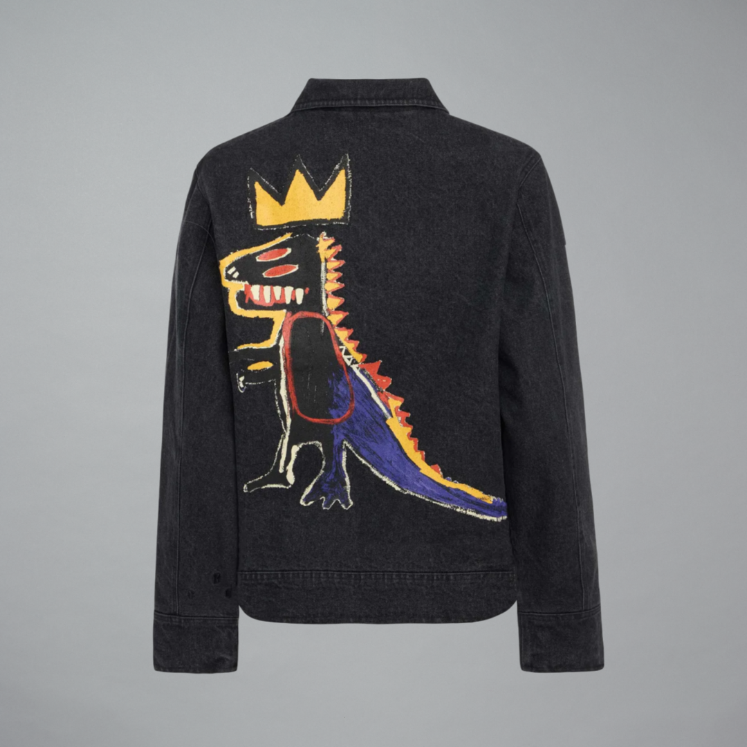 A black denim jacket shown from the back, featuring Jean-Michel Basquiat's Pez Dispenser on a gray background