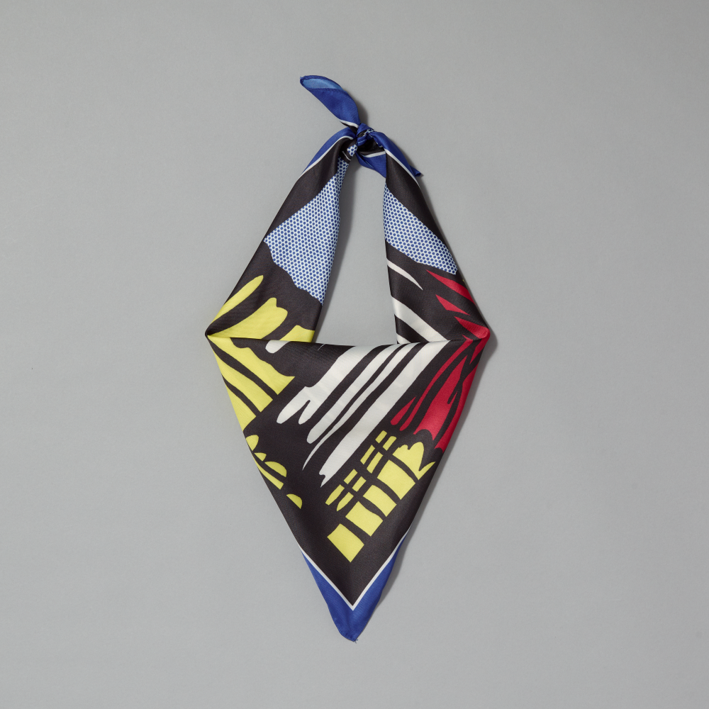 A square silk scarf tied in a knot with a vibrant graphic print of Roy Lichtenstein's work Little Big Painting displayed flat against a neutral gray background