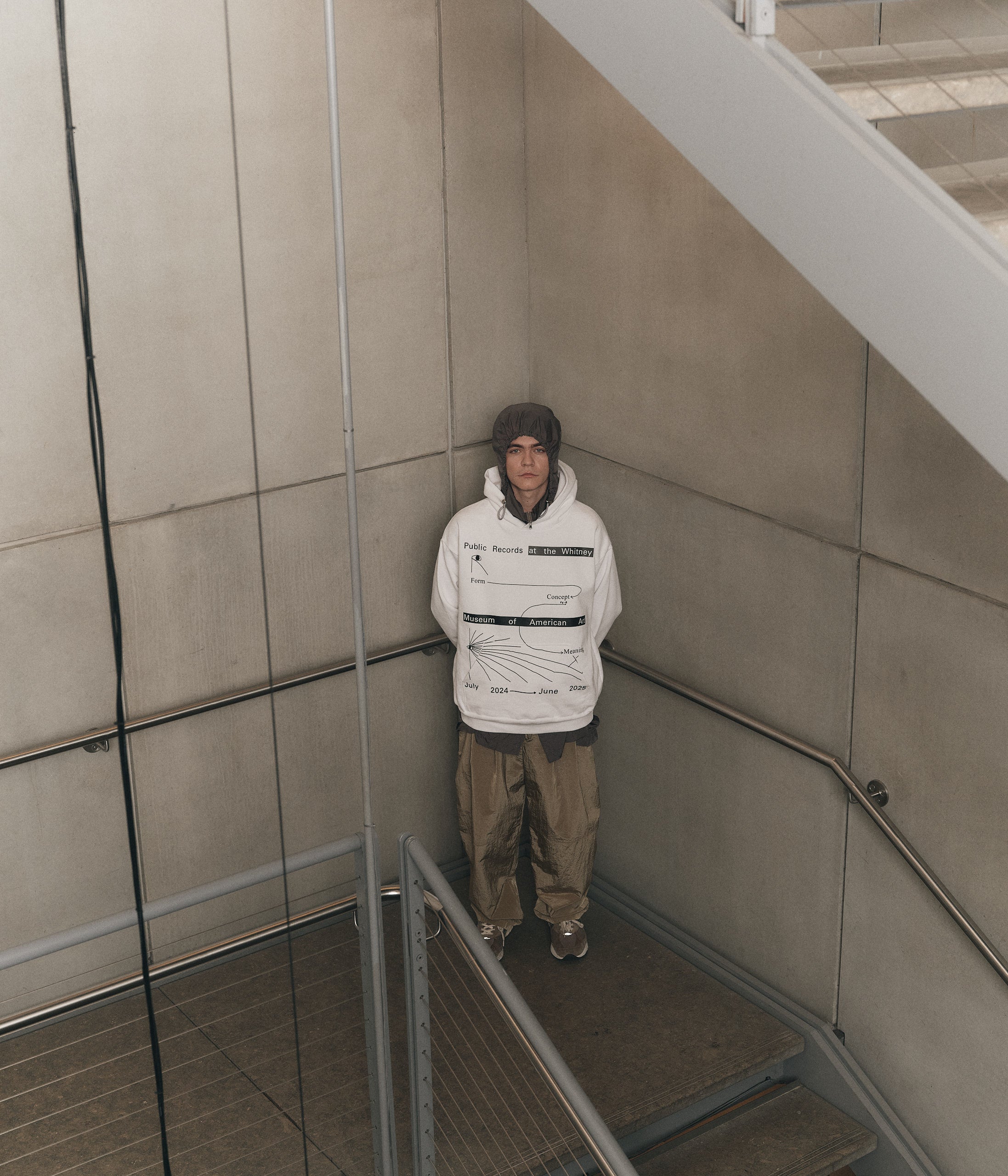 Model wearing 100% fleece white hoodie featuring Public Records at the Whitney Museum of American Art July 2024 to June 2025 in black text