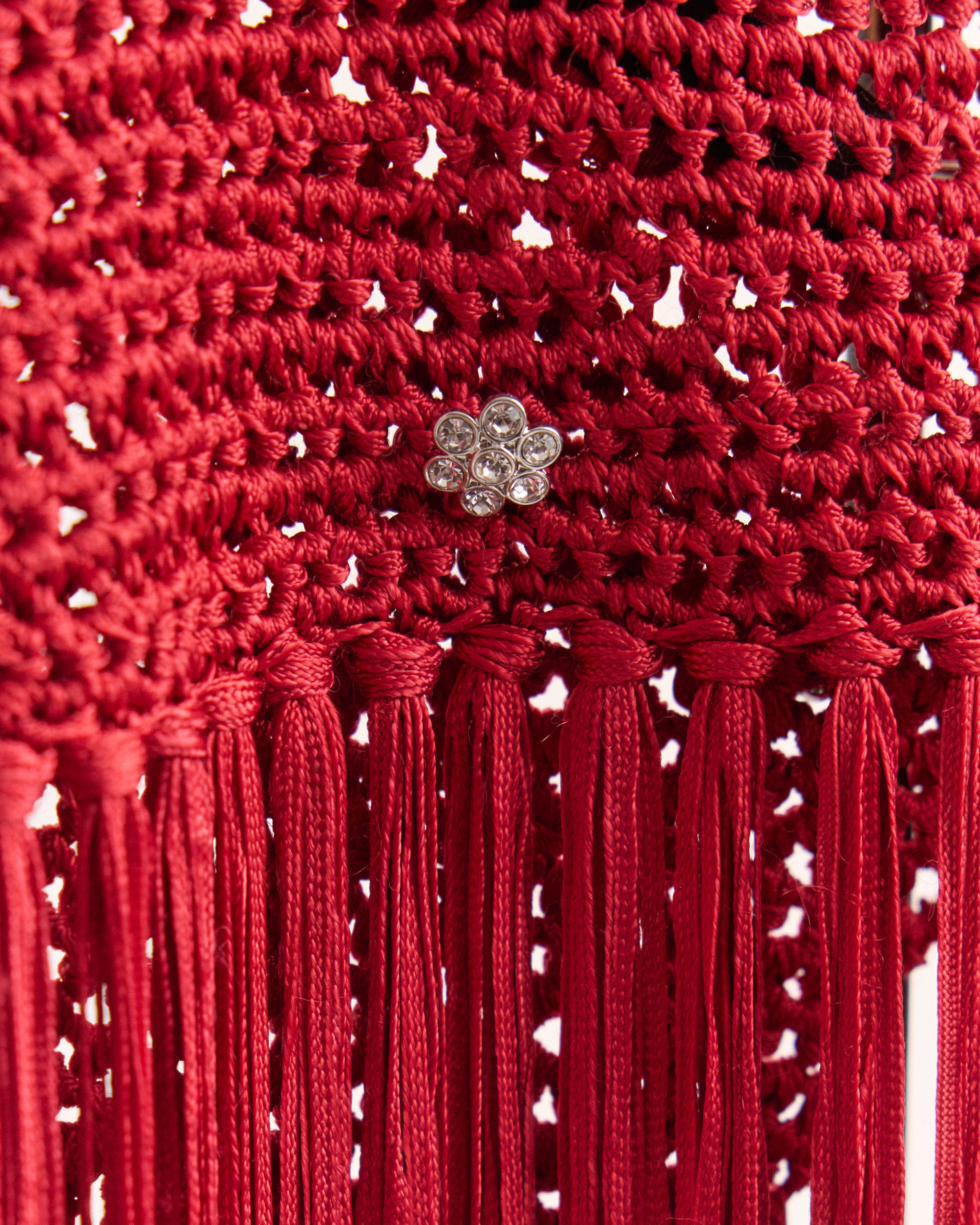Close-up of a red fringe skirt with tassels and a decorative rhinestone floret.