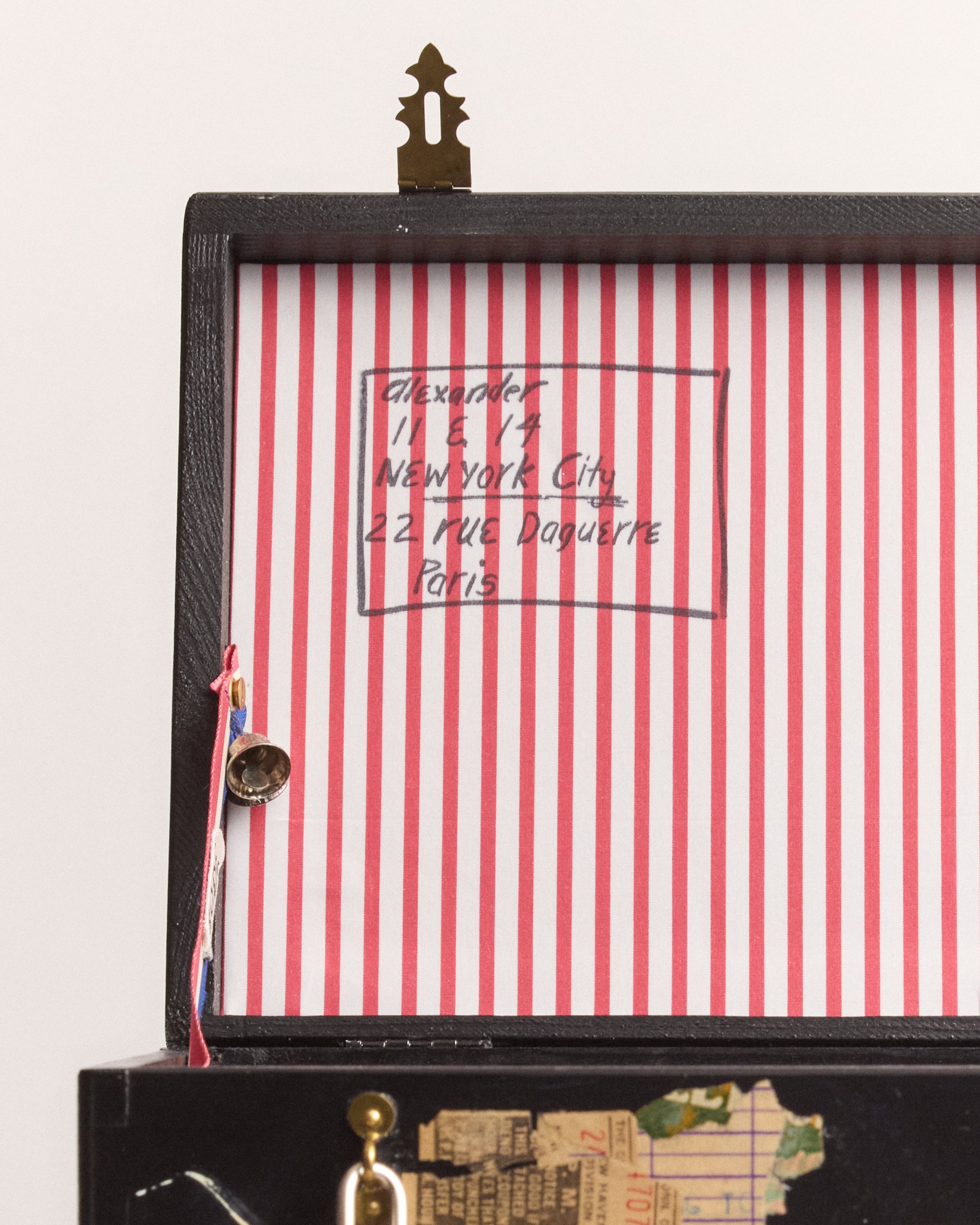 Close-up of a vintage-style suitcase box with red and white striped interior and gold accents.