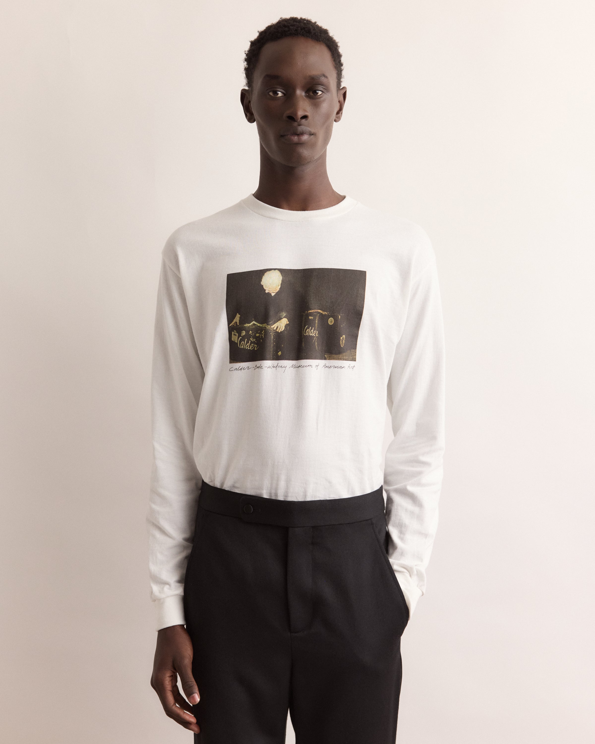 Man wearing a white long-sleeve shirt with a graphic design on a beige background