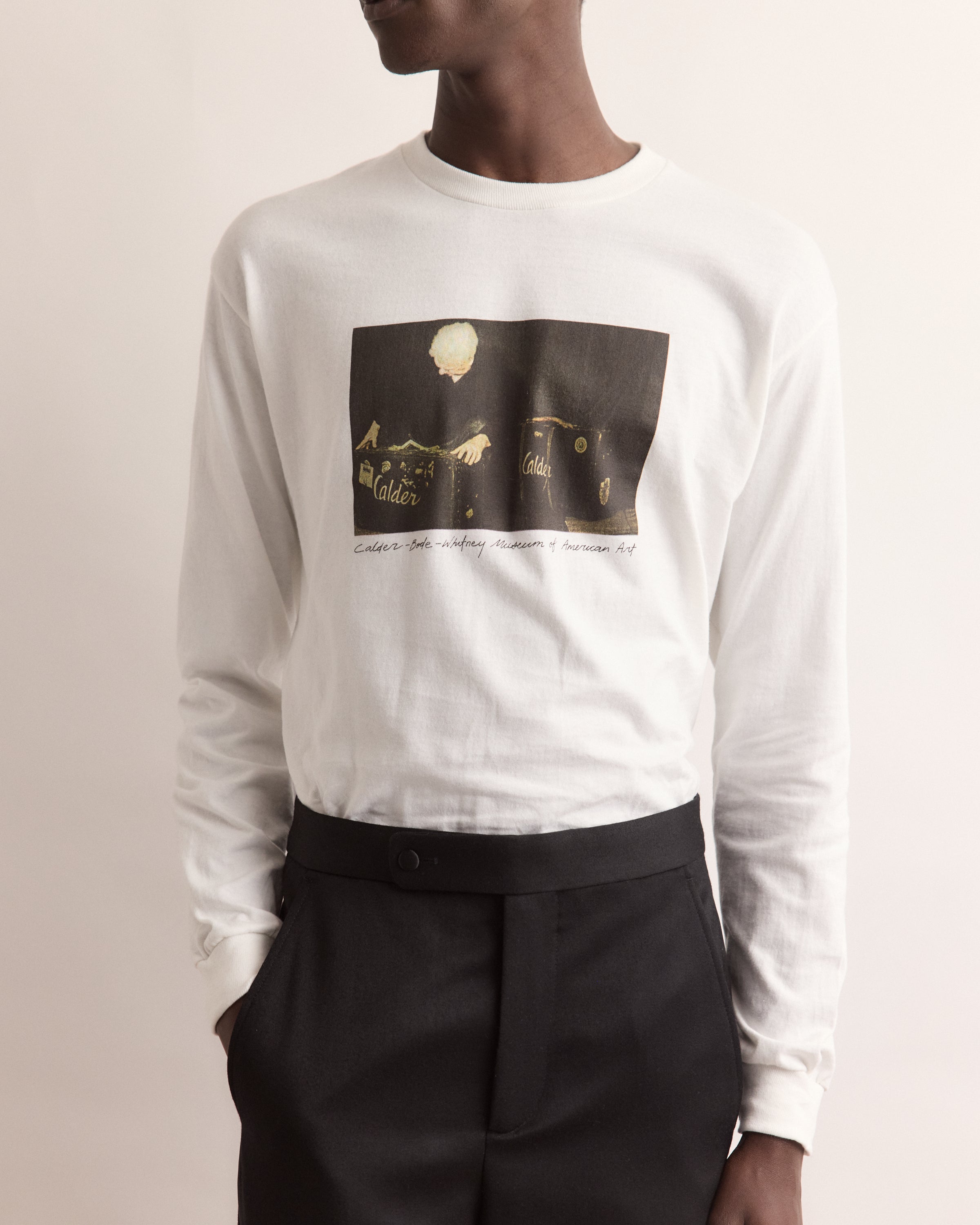 Person wearing a white long-sleeve shirt with a graphic design on a plain background