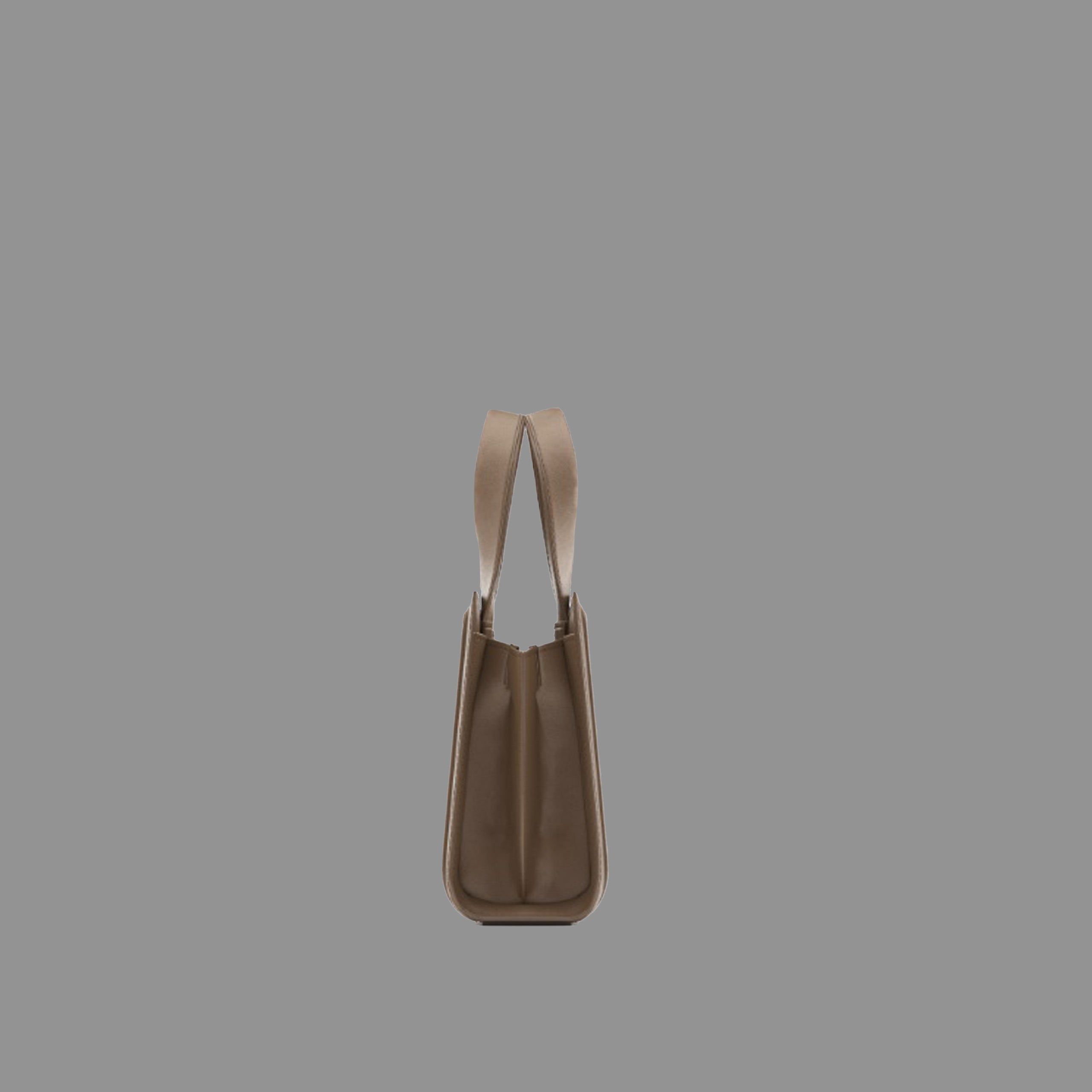 Side view of camel leather handbag with thin straps on a gray background