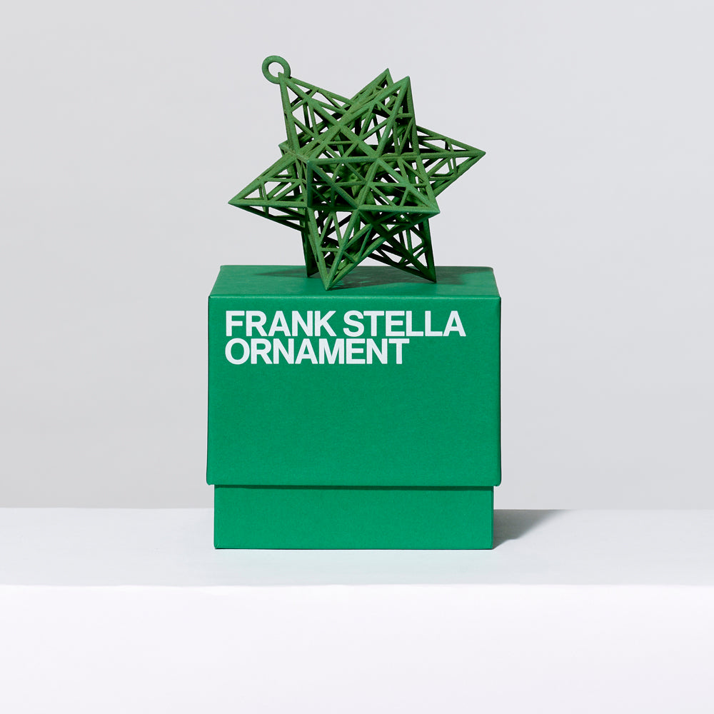 3-D printed plastic Frank Stella star ornament in green on top of gift box. Measures approximately 4" x 4" x 4"