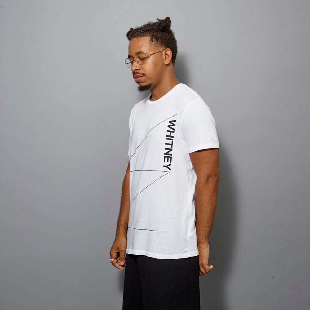 Model wearing 100% cotton white t-shirt with the Whitney responsive W logo in black text across the front.