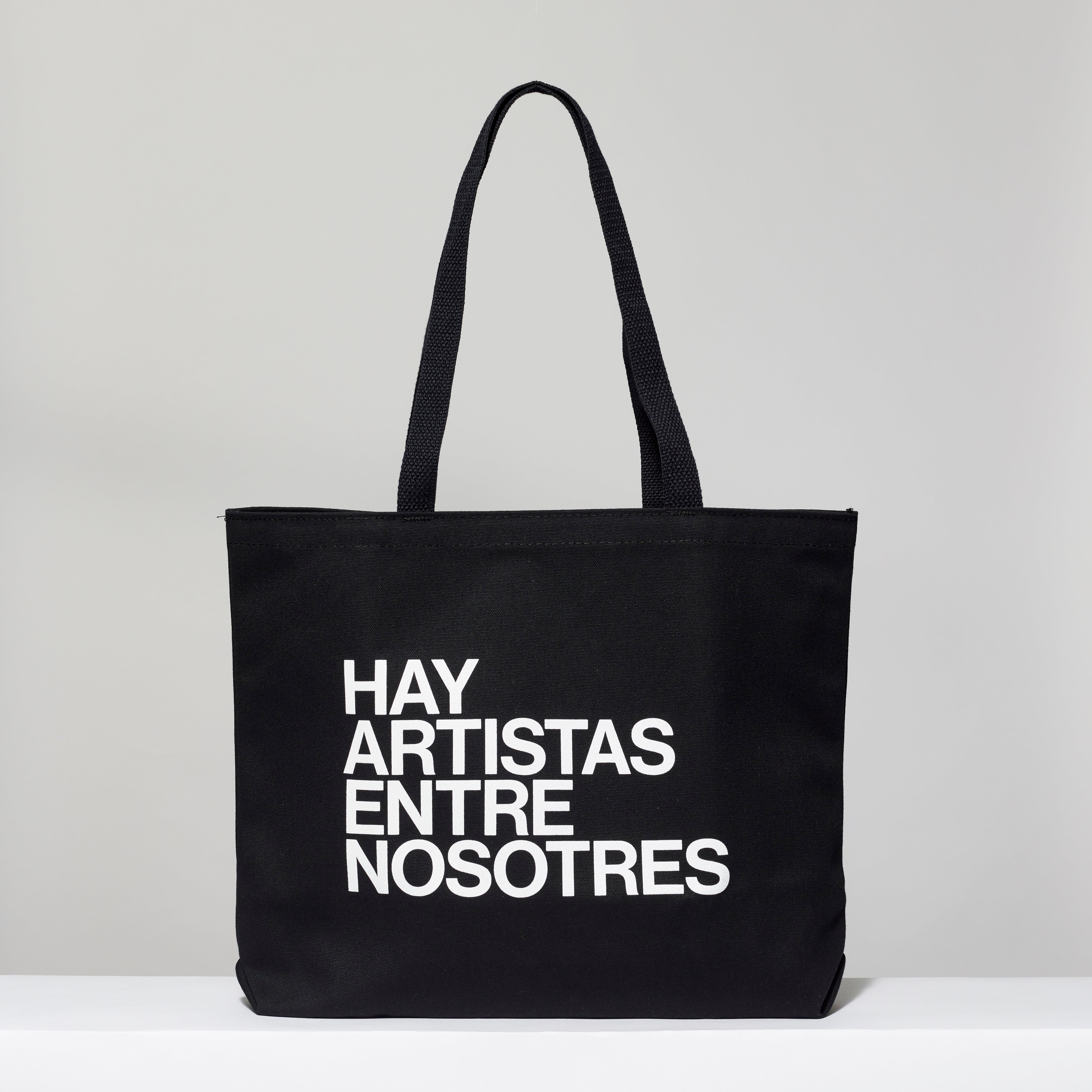 100% cotton black tote with Hay Artistas Entre Nosotres screen printed in white text. Measures 18" x 14". 3.5" gusset