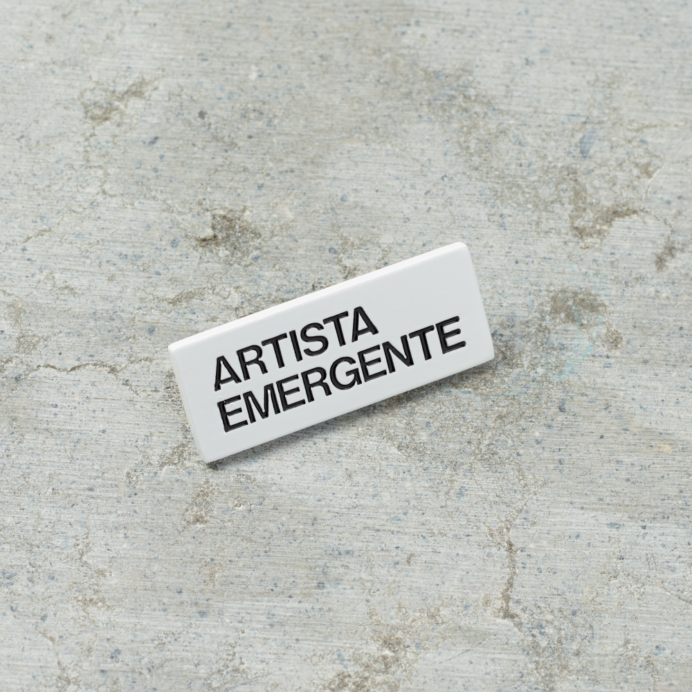 Black nickel plated brass and hard enamel pin that reads Artista Emergente