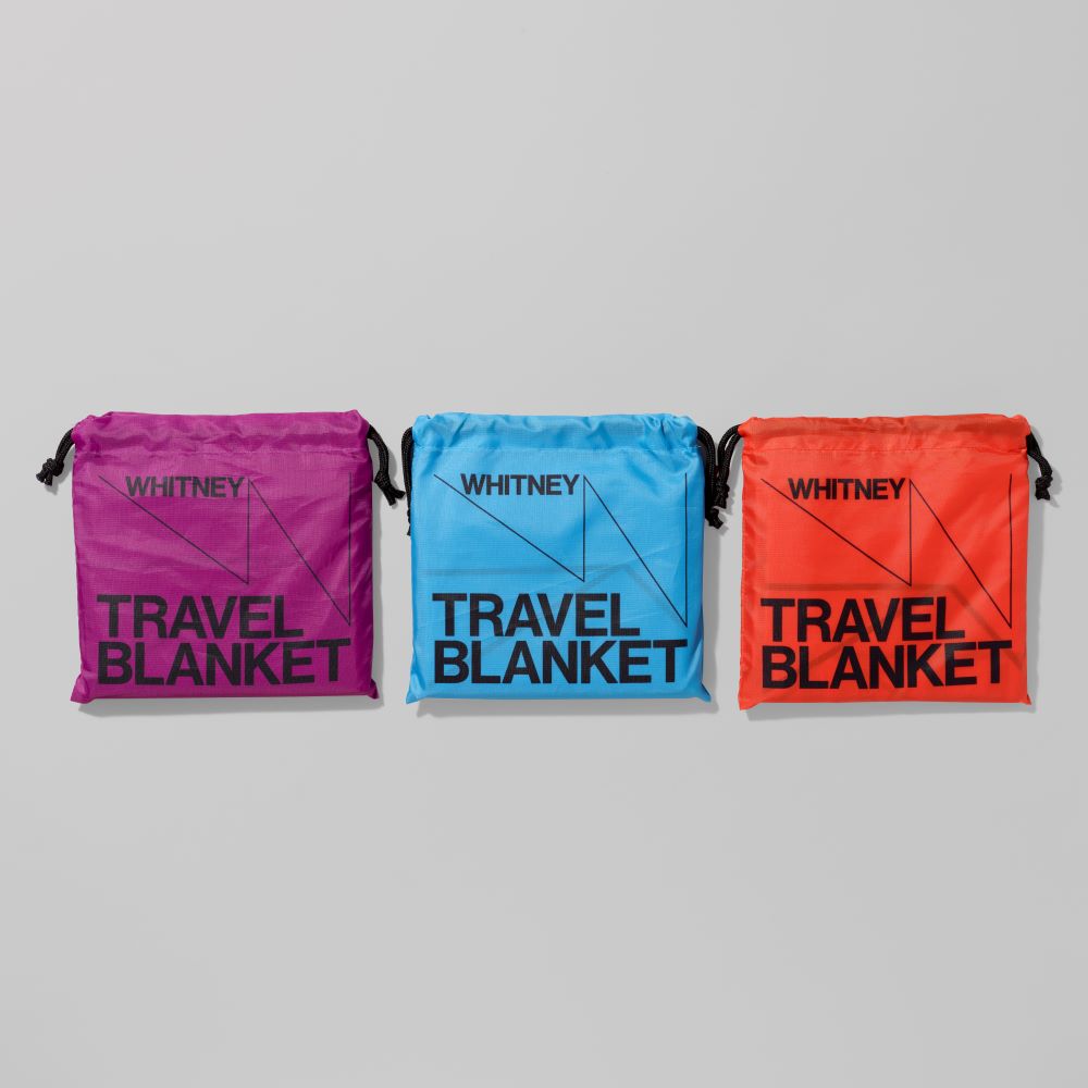 Purple, Blue, and Orange pouches containing ripstop polyester Whitney travel blankets that measure 59" x 59"