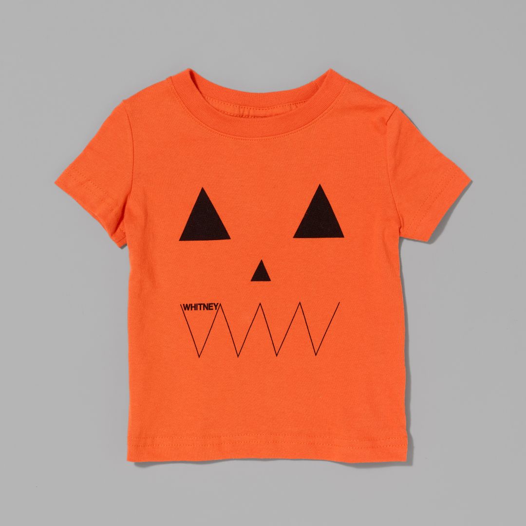 Orange t-shirt with black pumpkin face design on a gray background