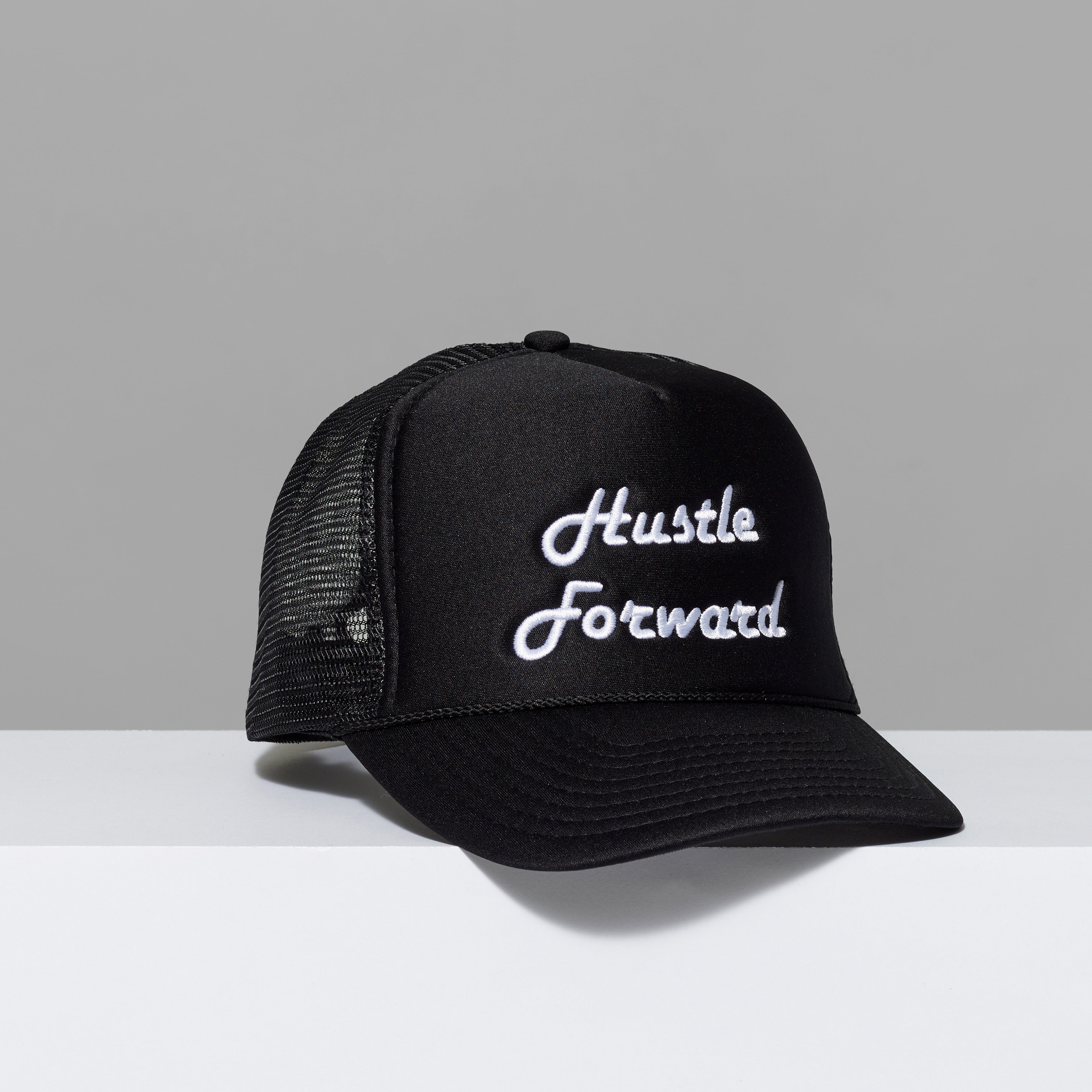 Black baseball cap with Hustle Forward embroidered in white stitching.
