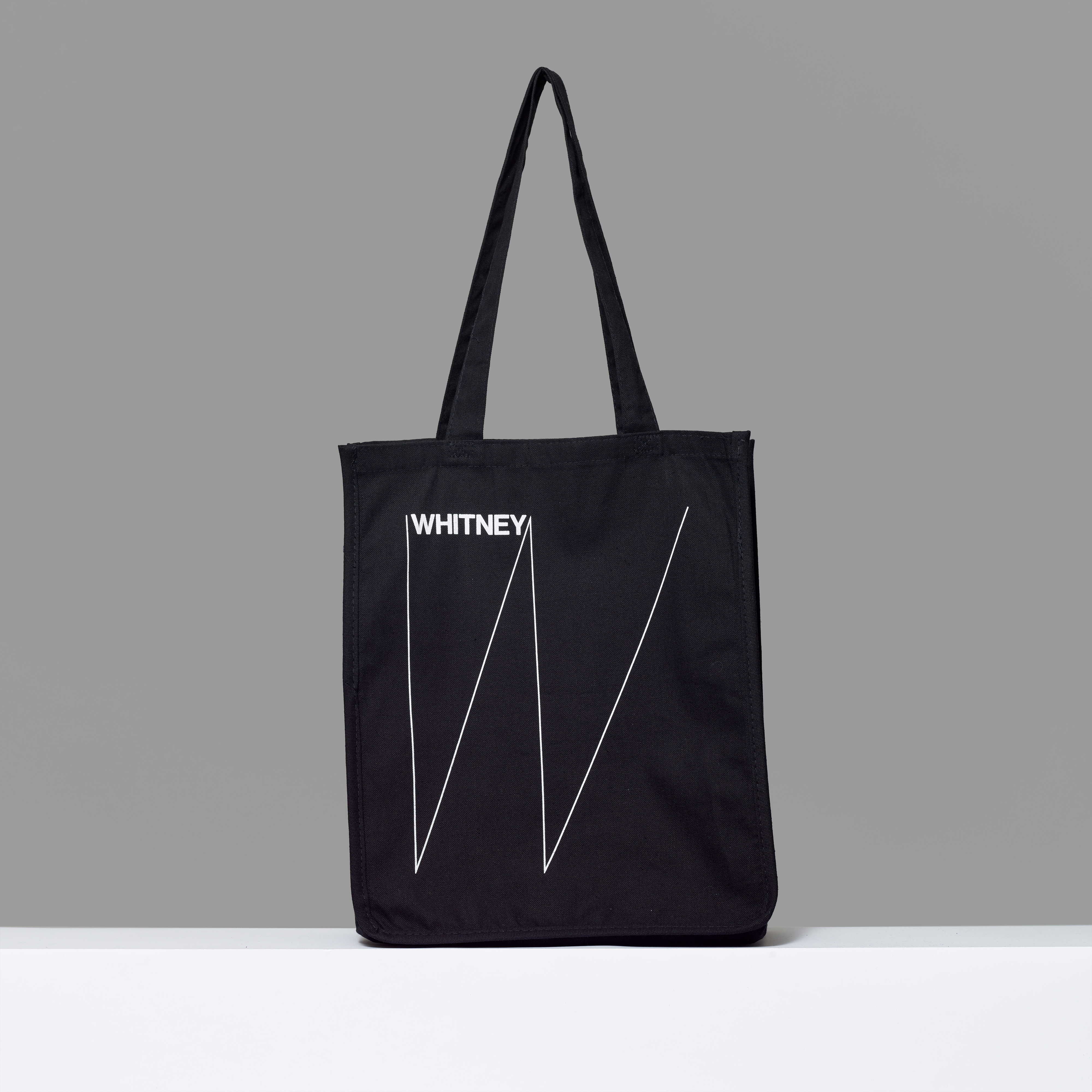 100% cotton black tote featuring Whitney logo in white text. 15" H x 14.25" L x 5" W.