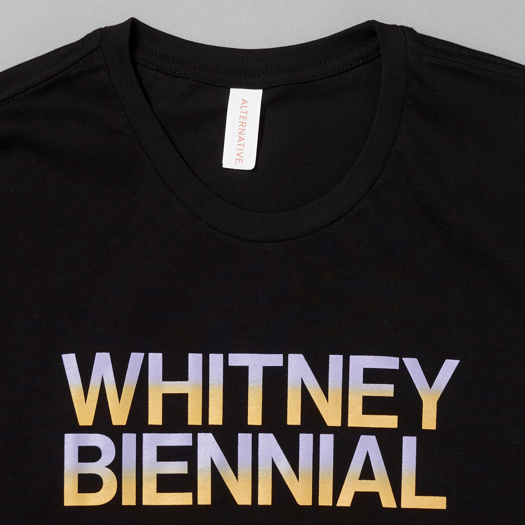 100% cotton black t-shirt with Whitney Biennial screen printed in purple and orange gradient colors