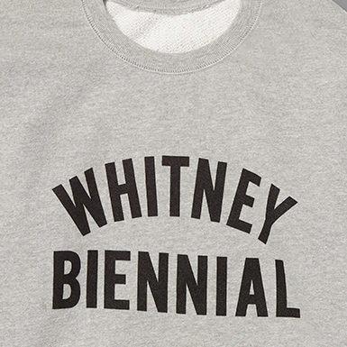 Gray sweatshirt with 'WHITNEY BIENNIAL' text on a gray background