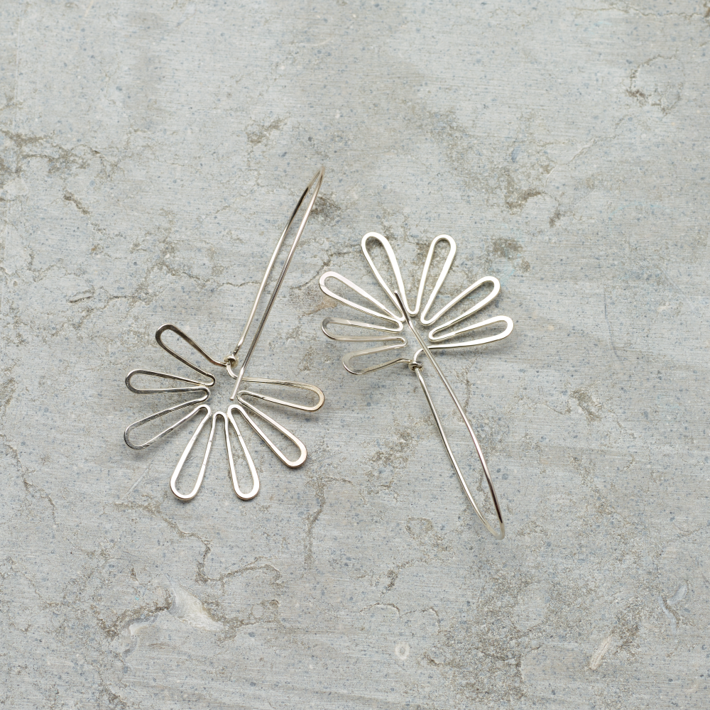 Silver floral earrings on a textured gray surface