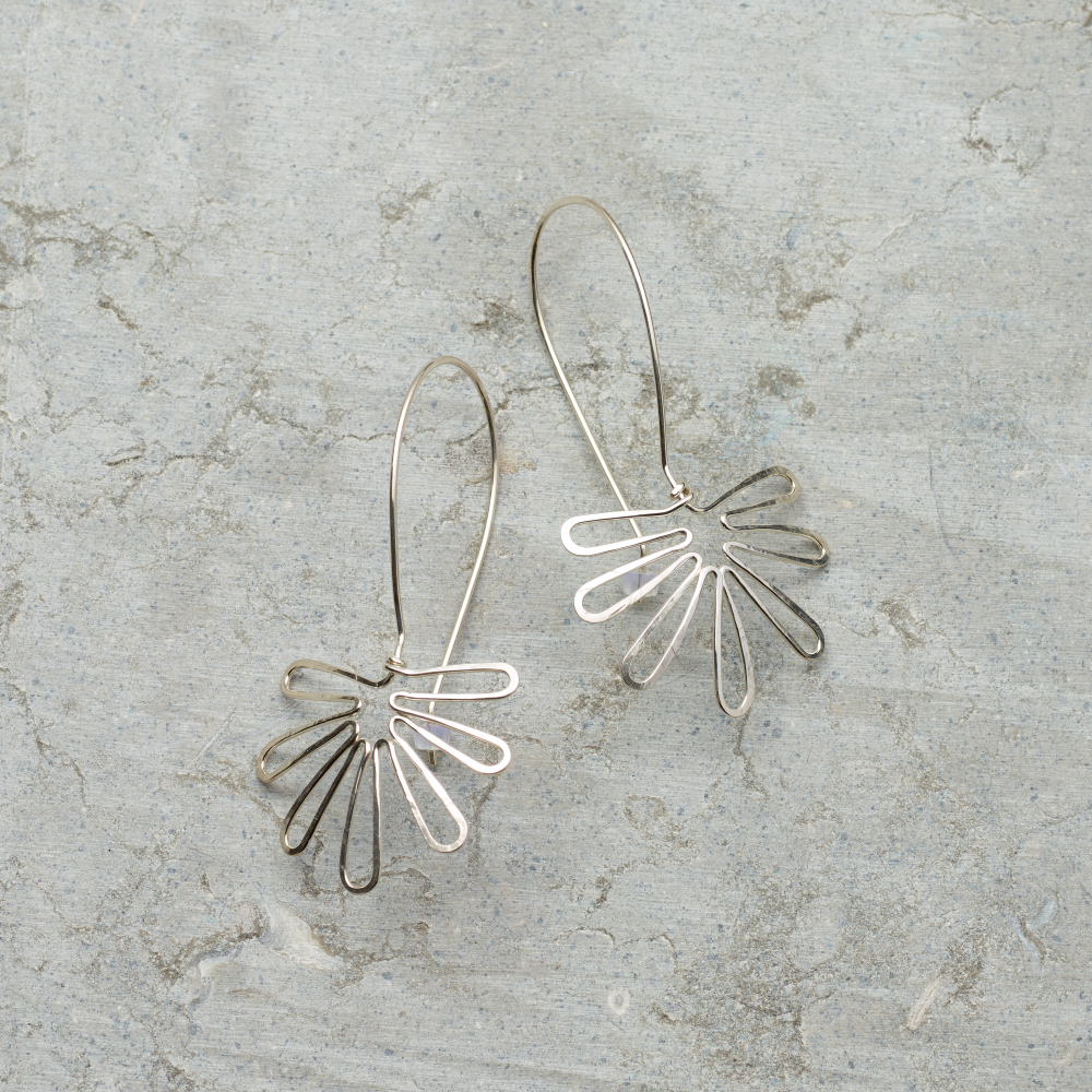 Silver wire earrings on a textured gray surface