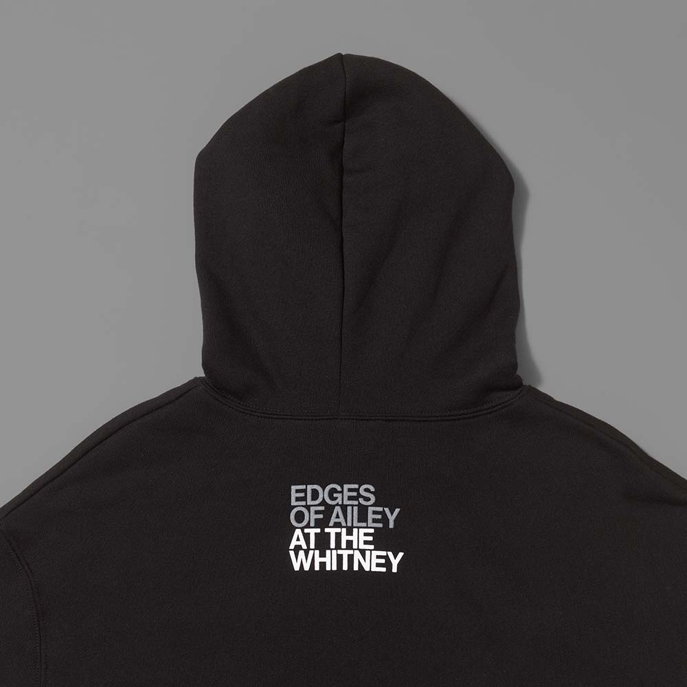 Back of the 52% cotton, 48% polyester black cropped hoodie with Edges of Ailey in gray text and At The Whitney in white text