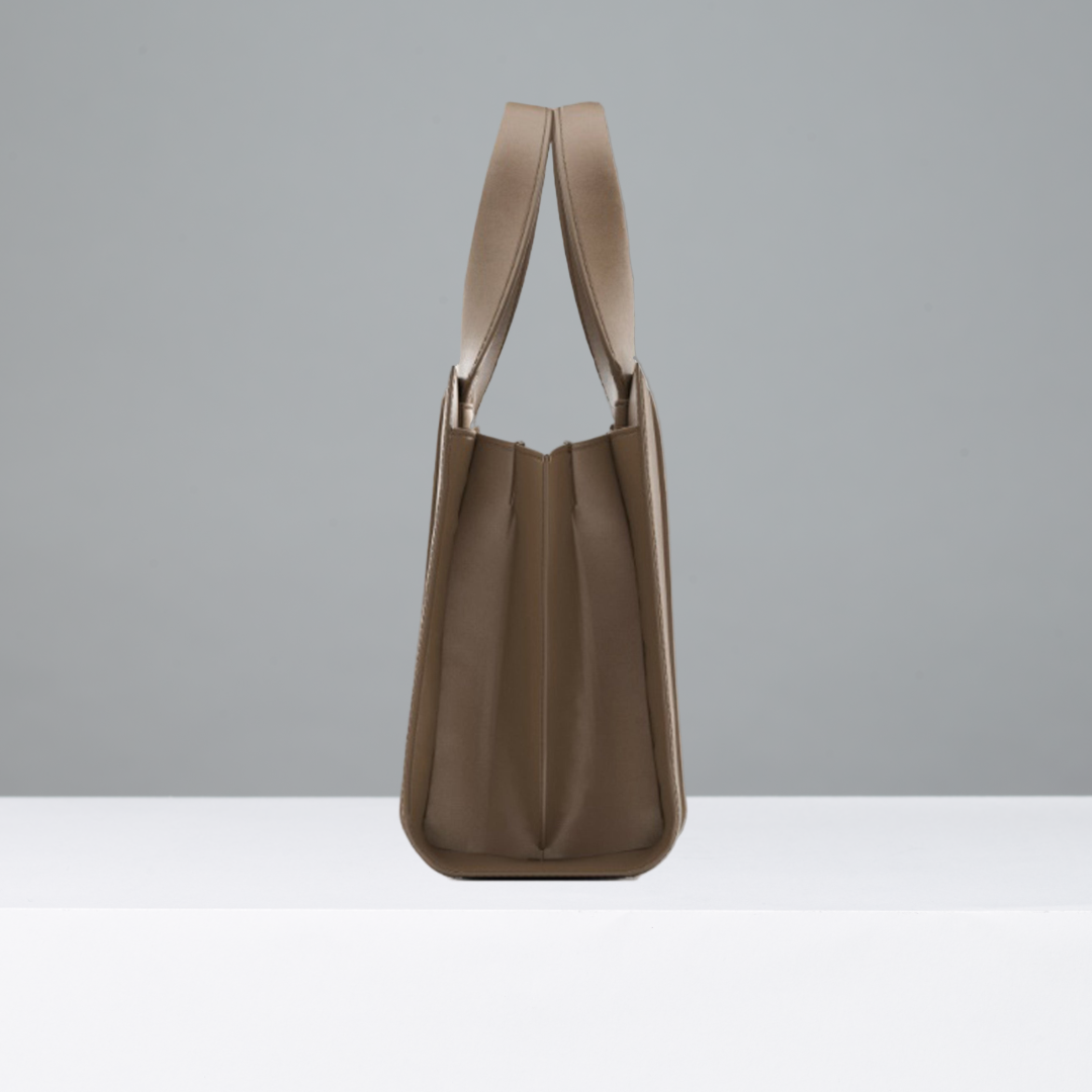Side view of camel leather handbag with thin straps on a gray background