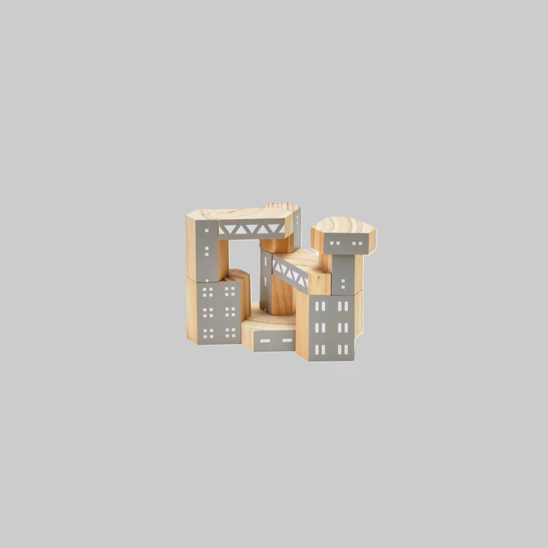 Wooden block toy shaped like a cityscape on a gray background