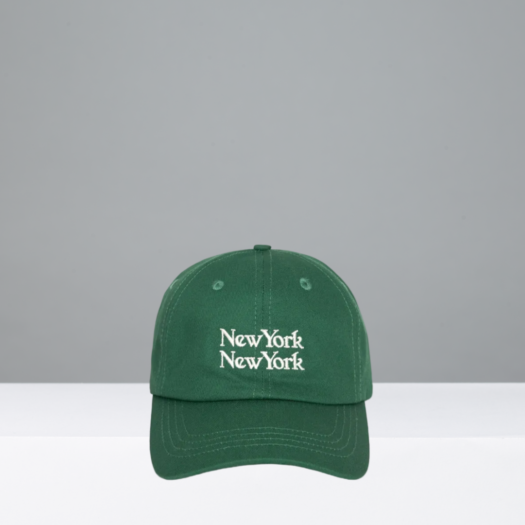 A dark green baseball cap with 'New York New York' embroidered in white Gothic-style lettering on the front, displayed against a neutral gray background.