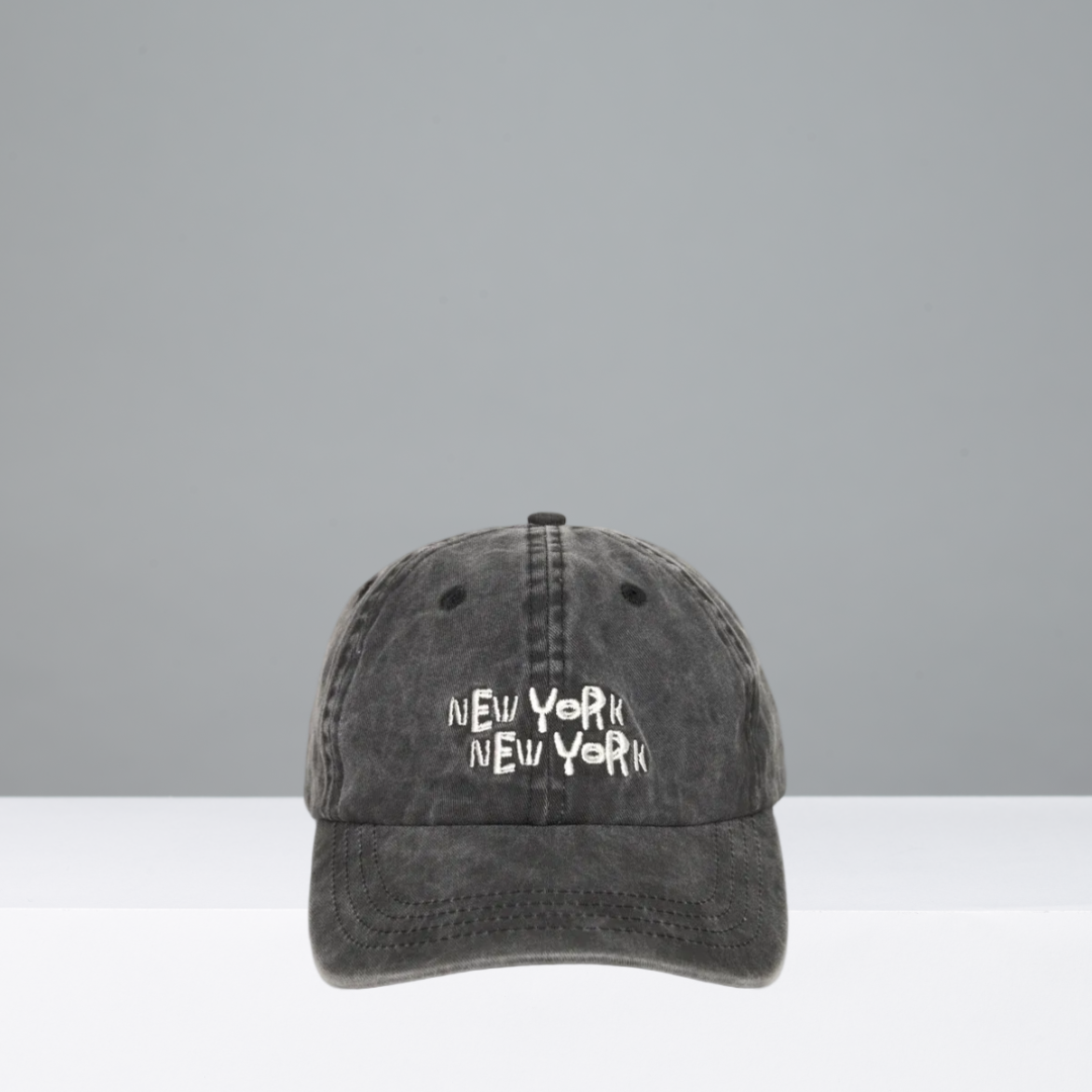 A dark gray acid-wash baseball cap with 'NEW YORK NEW YORK' embroidered in white across the front, displayed against a neutral gray background.