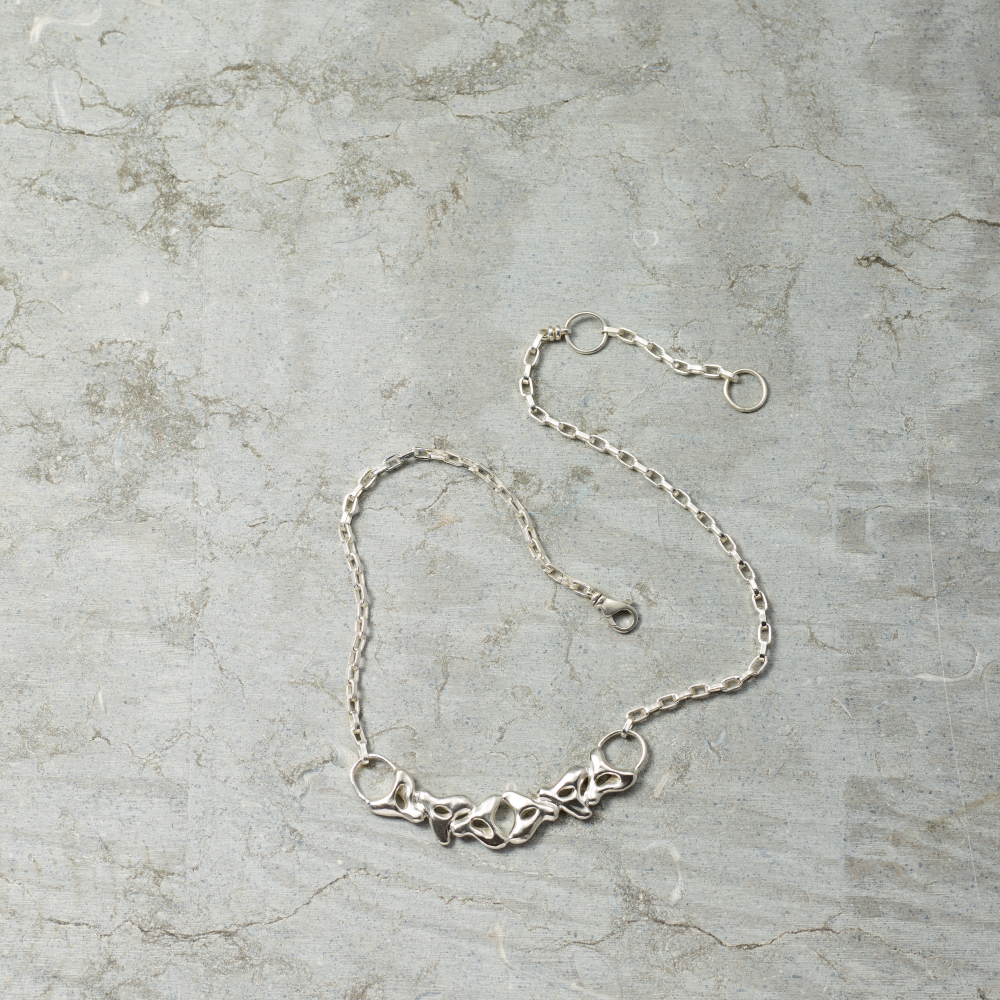 Silver chain necklace on a textured gray surface