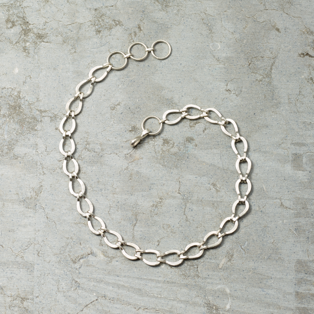 Silver chain necklace on a textured gray surface