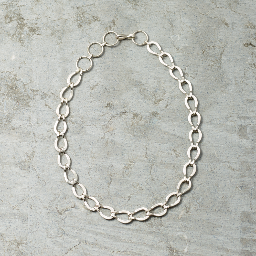 Silver chain necklace on a textured gray surface