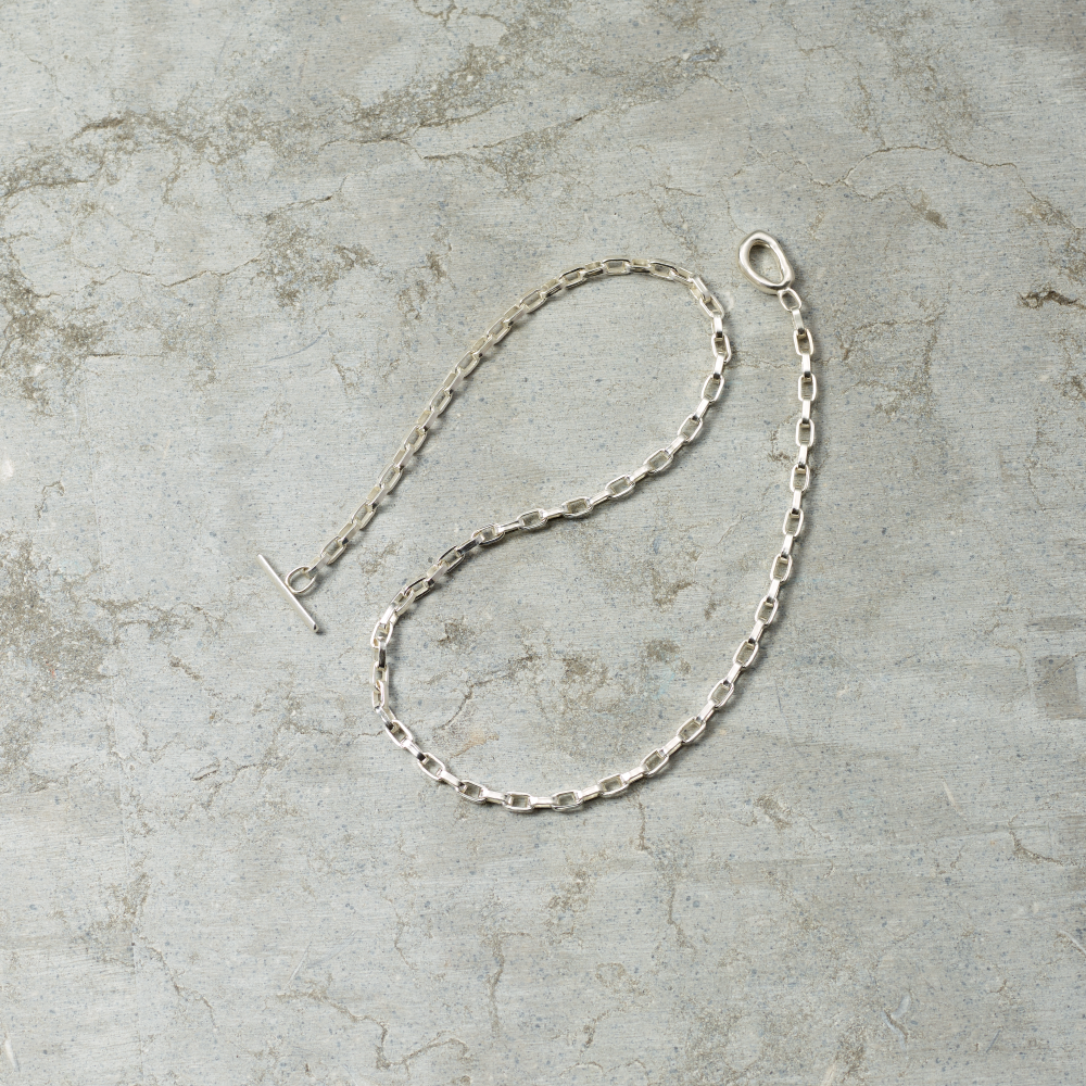 Silver chain necklace on a textured gray surface