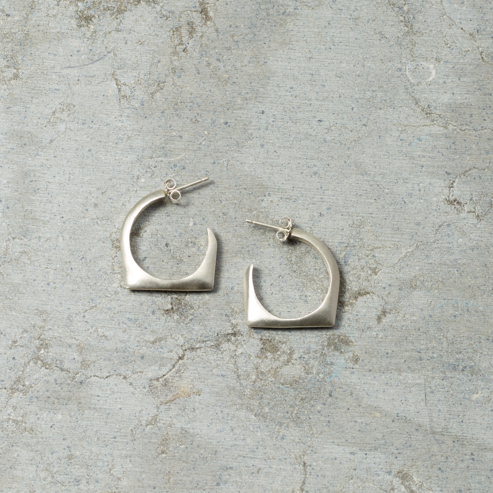 Silver hoop earrings on a textured gray surface