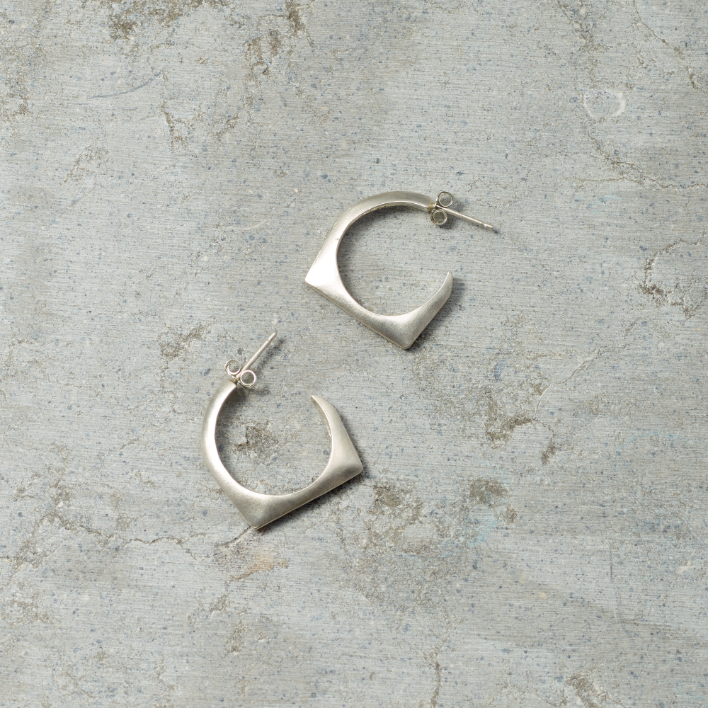 Silver hoop earrings on a textured gray surface