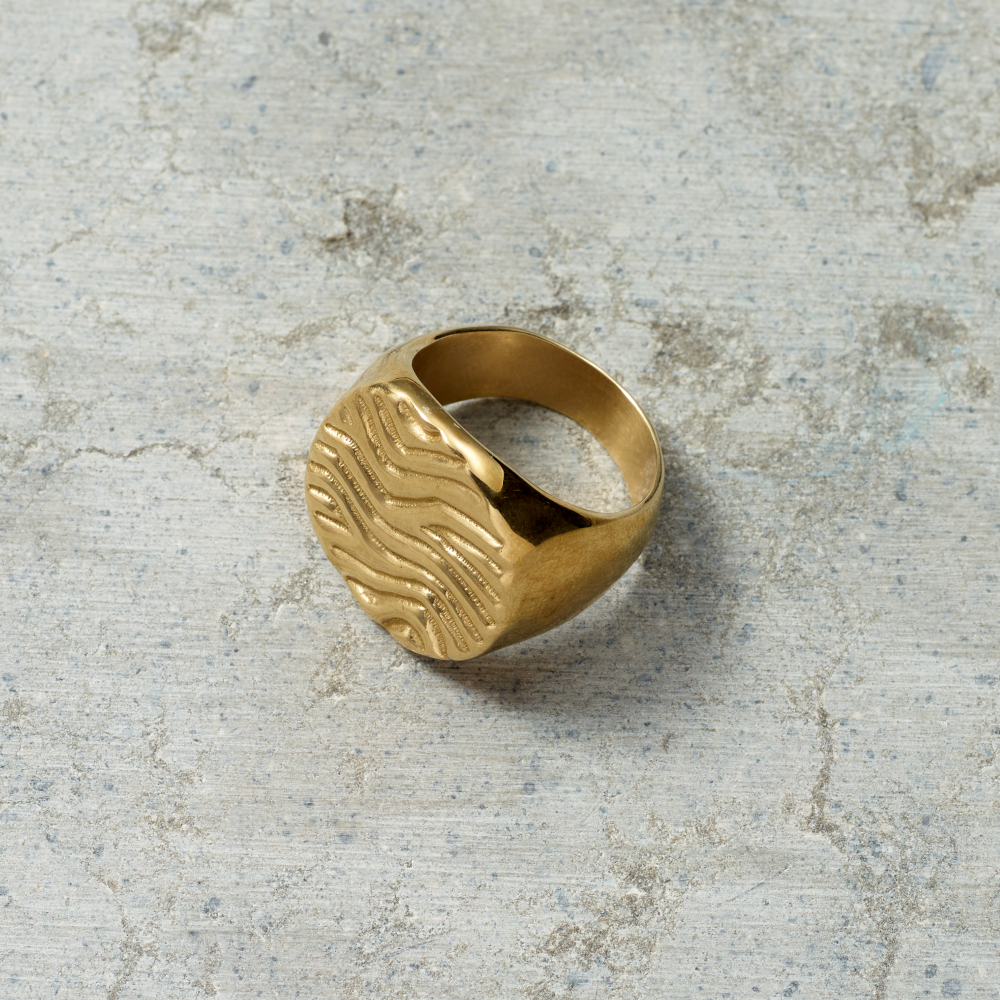 Gold ring with a textured design on a textured gray surface