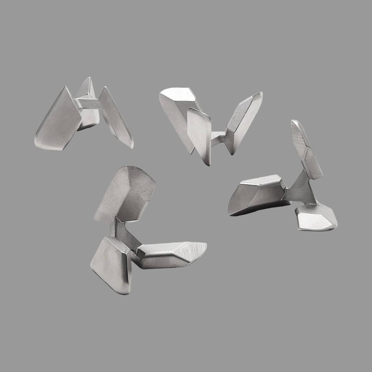 Set of four metallic geometric objects on a gray background