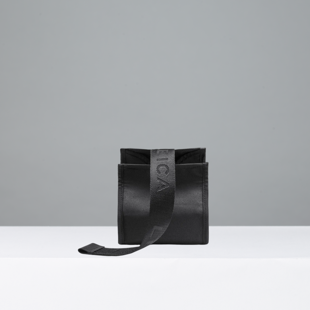 Black camera pouch with a strap on a gray background