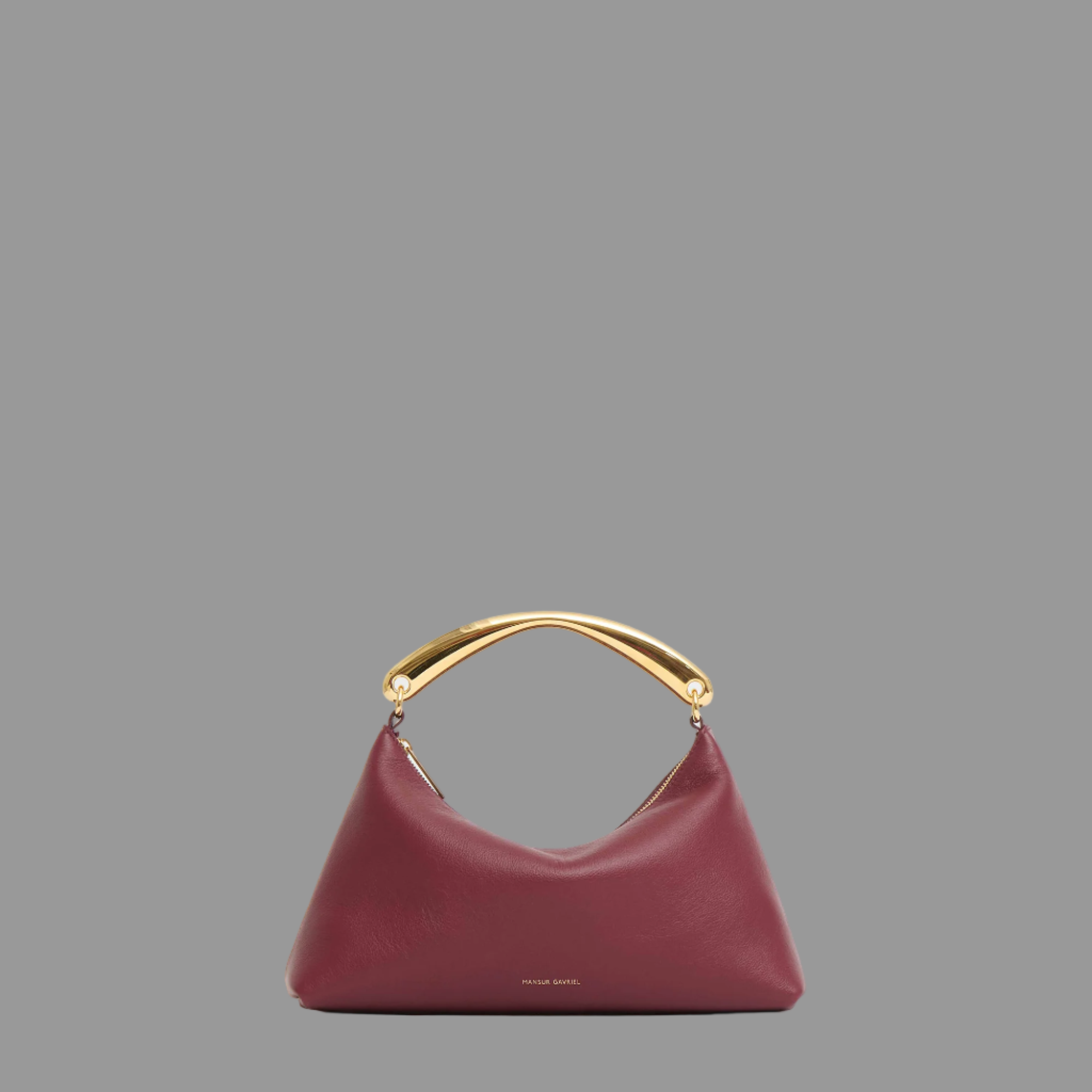 Oxblood handbag with gold handle on a light gray background