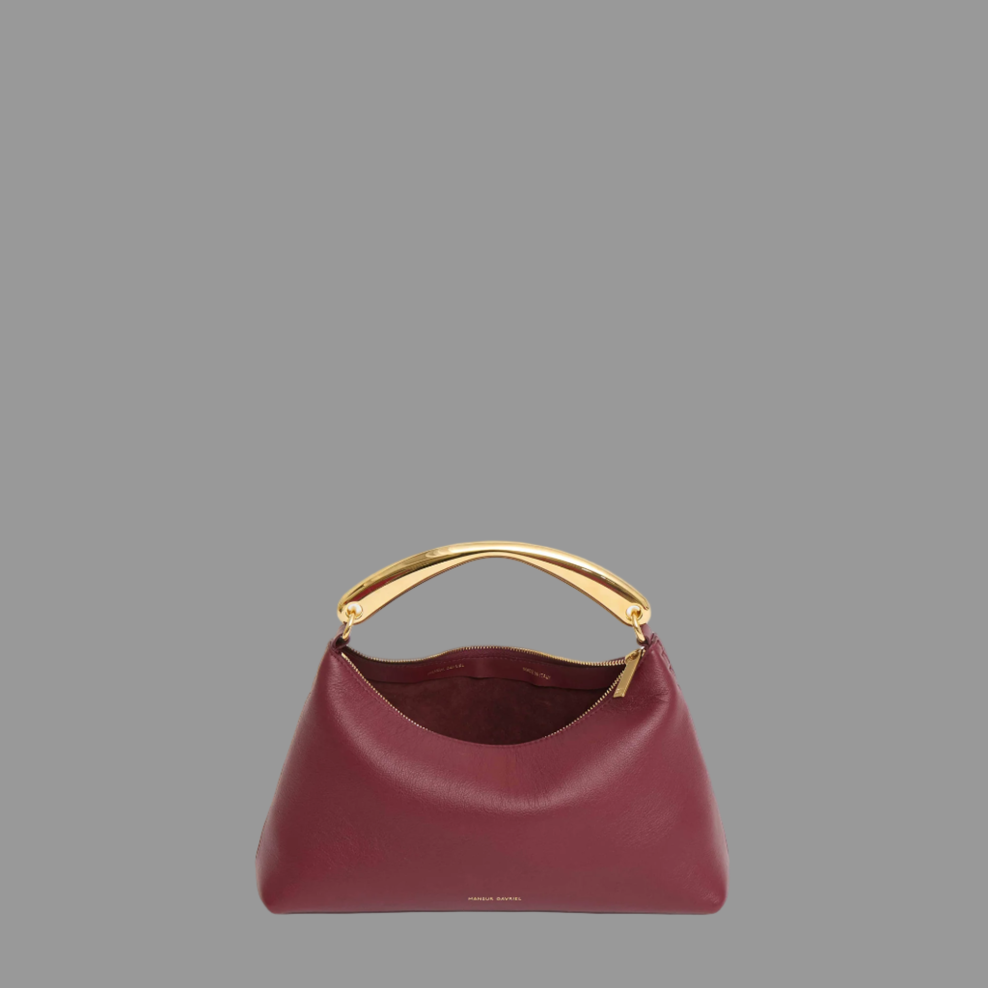 Oxblood handbag with gold handle on a light gray background