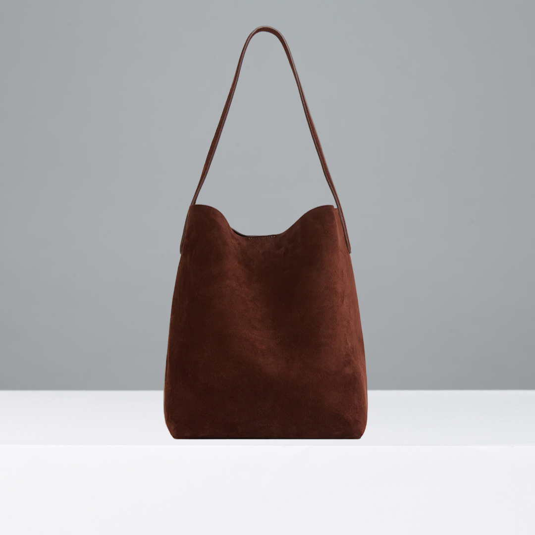 Chocolate suede leather bag on a grey background
