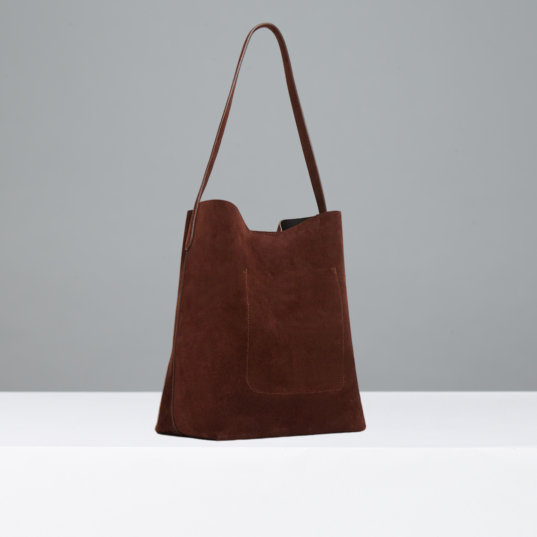 Chocolate suede leather bag on a grey background