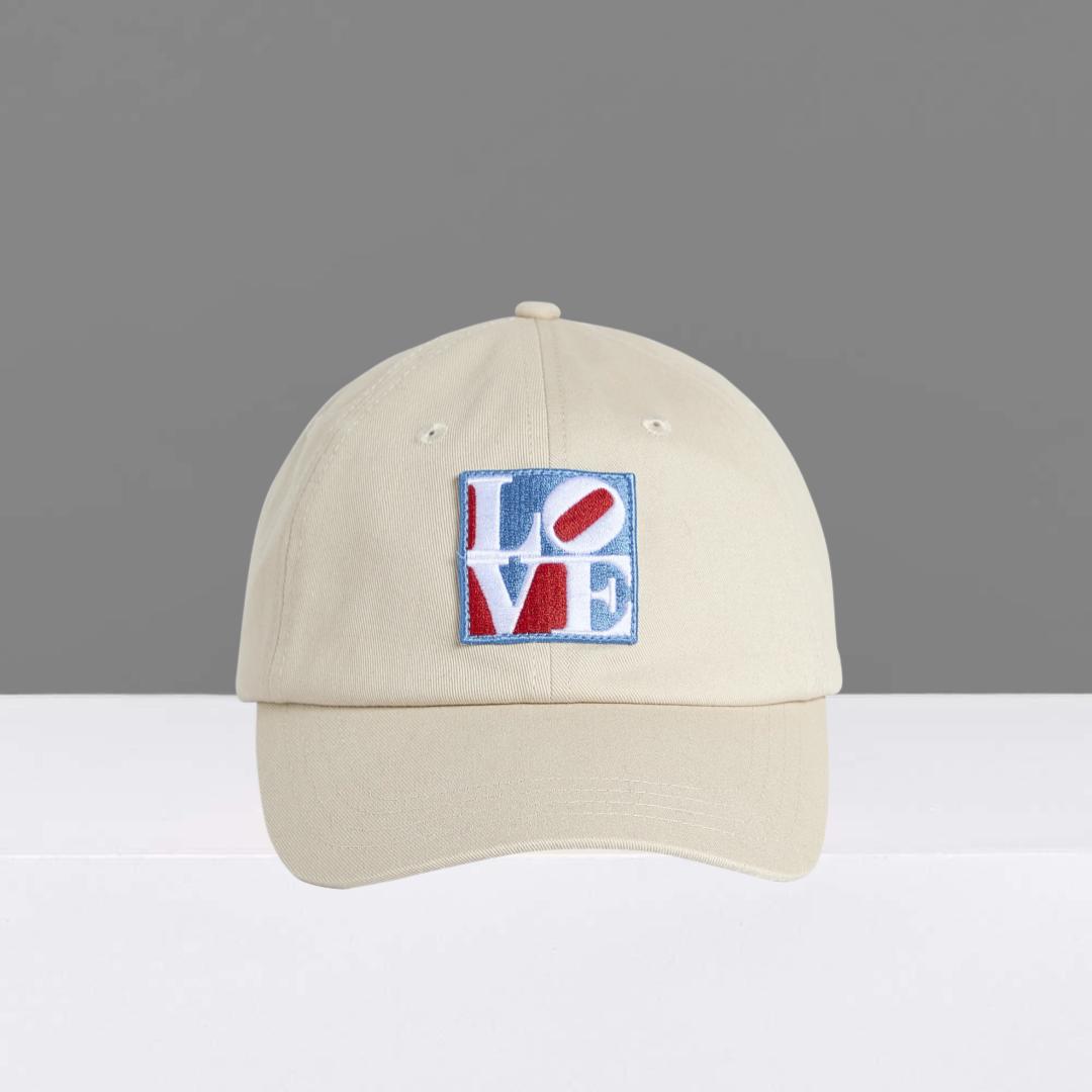 Stone colored cap with Robert Indiana's colorful 'LOVE' patch on a gray background
