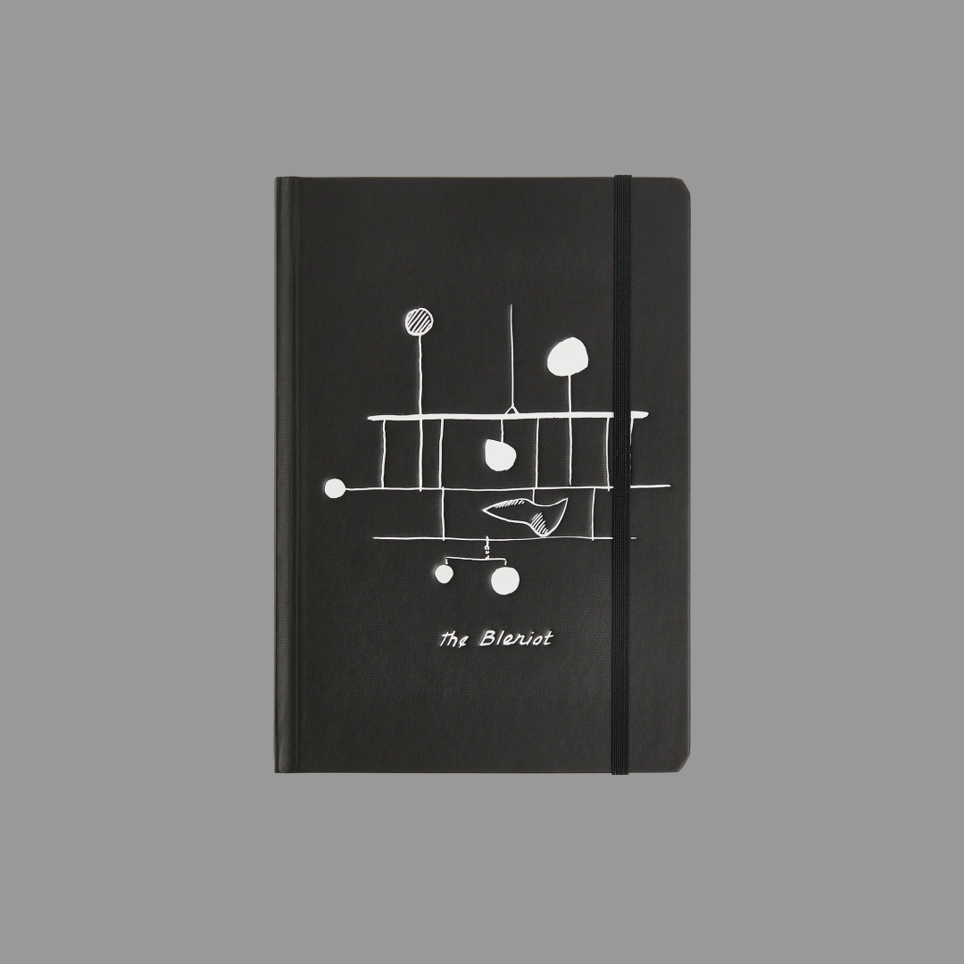 Black notebook with white abstract design and 'The Bleriot' branding on a gray background