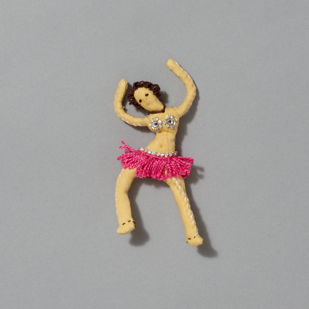 Small brooch of a dancer with a pink skirt on a gray background