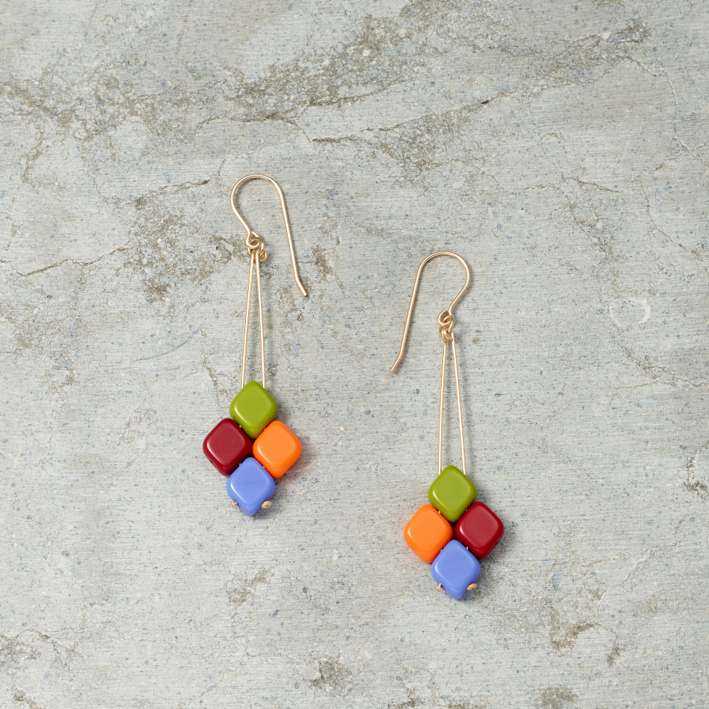 Colorful square bead earrings on a textured gray surface