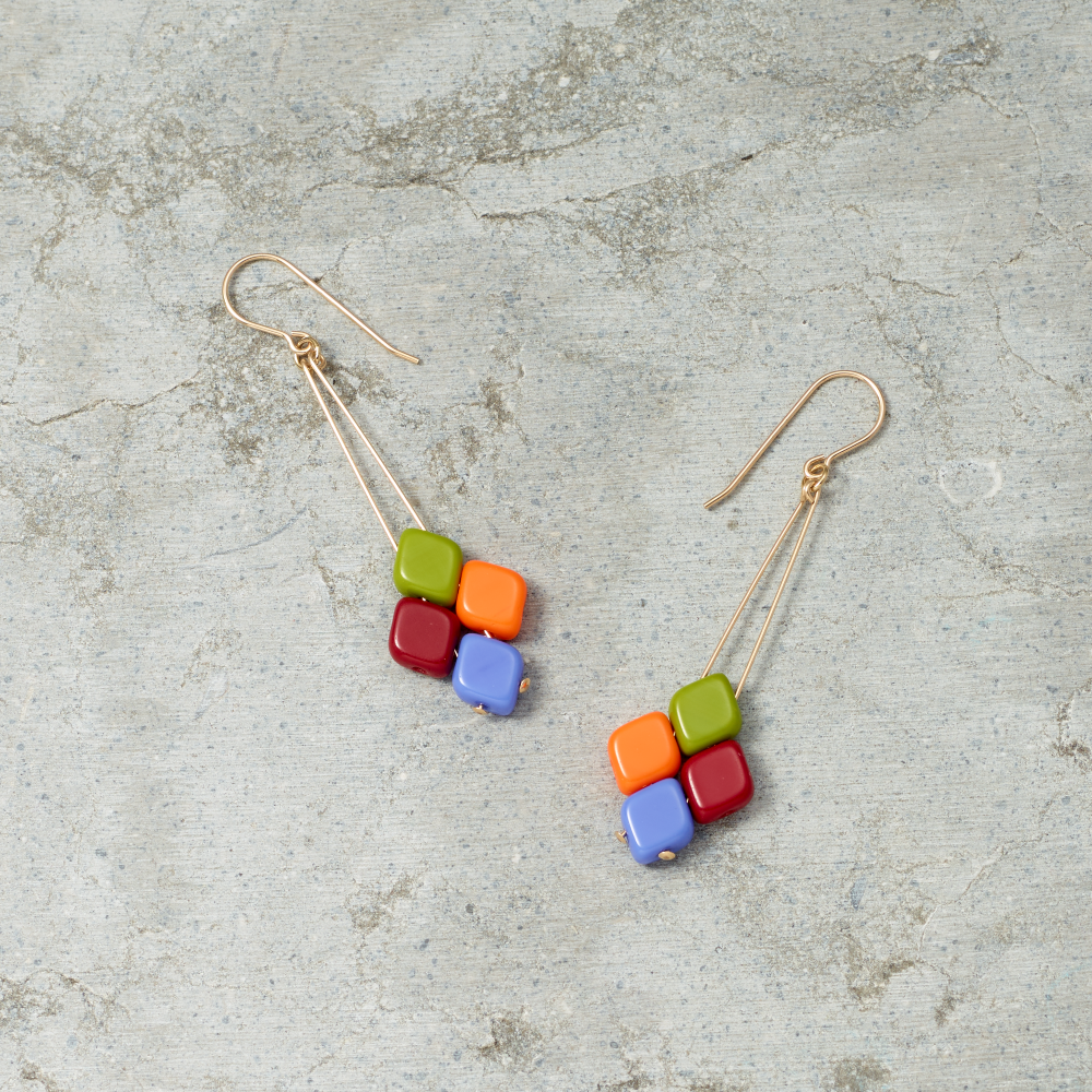 Colorful square bead earrings on a textured gray surface